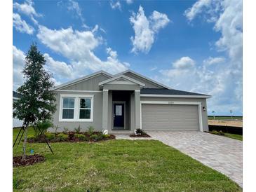 Beautiful one-story home with gray stucco, manicured lawn, and paver driveway to a two car garage at 2009 Stone Wall Ct, Lake Hamilton, FL 33851