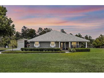 Charming one-story home with landscaped lawn and a well-maintained yard and separate garage at 23203 Outback Ln, Eustis, FL 32736