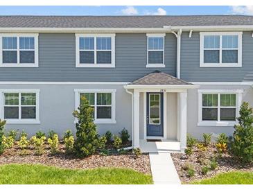 Charming townhouse with a blue front door, well-maintained landscaping, and gray siding at 2831 Camellia Flower St, Apopka, FL 32703