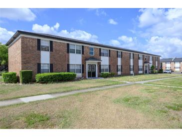 Traditional two-story brick apartment building with dark shutters and trimmed green shrubs at 5325 Curry Ford Rd # G202, Orlando, FL 32812