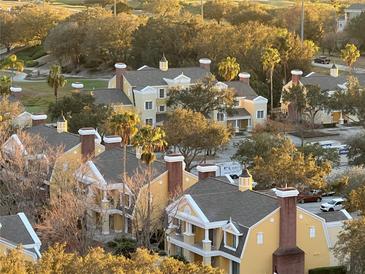Beautiful aerial view showcasing yellow condos, lush greenery, and palm trees, near a golf course at 7518 Seven Eagles Way # 201, Reunion, FL 34747