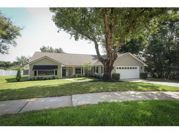 Charming one-story home with a well-maintained lawn, mature trees, and an attached two-car garage at 7703 Pine Vista Ct, Orlando, FL 32819