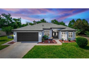 Charming single-story home featuring a well-manicured lawn, gray roof, and attached two-car garage at 825 White Birch Ct, Orange City, FL 32763