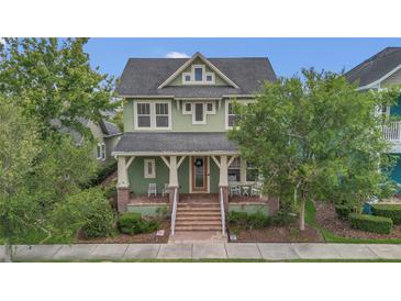 Charming two-story home featuring a welcoming front porch, well-maintained lawn, and mature trees, offering a delightful curb appeal at 8679 Laureate Blvd, Orlando, FL 32827