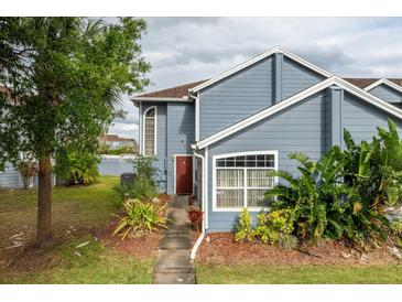 Charming townhome with a blue exterior, mature landscaping, and a welcoming entrance at 135 Orchid Dr, Davenport, FL 33897