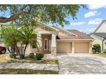 Charming home with a two-car garage, a covered porch, stone accents, manicured landscaping, and palm trees at 14537 Cheever St, Orlando, FL 32828
