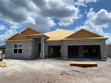 Exterior view of home under construction, showcasing the block structure and roof framework under a cloudy sky at 2703 Ravencliffe Ter, Oviedo, FL 32765