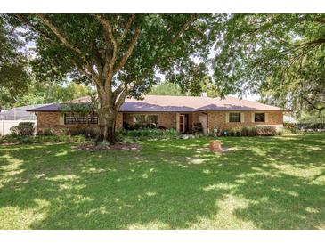 Charming brick home featuring a well-manicured lawn and mature trees providing shade at 429 Kimberly Ct, Sanford, FL 32771