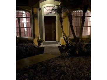 Home's inviting entryway with a decorative door, sidelight windows, and lush landscaping at 4920 E Lake Cove Blvd, St Cloud, FL 34771
