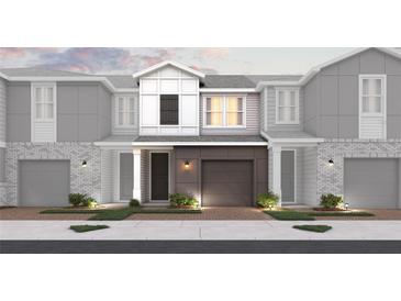 New construction townhomes featuring brick and modern grey siding, attached garages, and manicured landscaping at 555 Southern Edge Way, Sanford, FL 32771