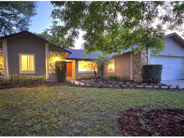 Charming home with stone accents, fresh landscaping, and warm lighting creating an inviting curb appeal at 8825 Larwin Ln, Orlando, FL 32817