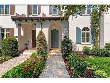 Charming home exterior with beautiful landscaping and inviting front entrance with arched door and paver walkway at 8848 Bismarck Palm Dr, Winter Garden, FL 34787