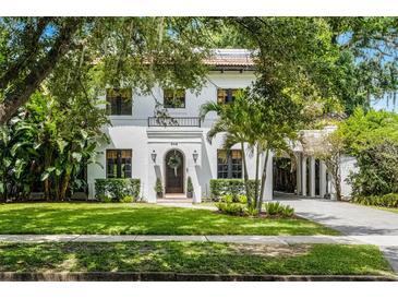 Stunning two-story home featuring a red tile roof, lush landscaping, and a porte-cochère at 906 Alhambra Ct, Orlando, FL 32804