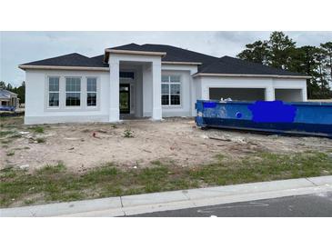 Under construction exterior of a white home with a three-car garage and large windows on a cloudy day at 960 Hawksnest Pt, Oviedo, FL 32765