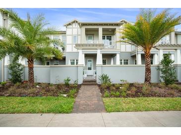 Attractive townhouse with palms, lawn and walkway to the front door at 13437 Granger Ave, Orlando, FL 32827