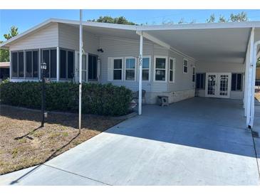 Well-maintained single-story home featuring a covered carport and enclosed sunroom, nestled amongst mature shrubs at 158 Rita Bee Ave, Davenport, FL 33897