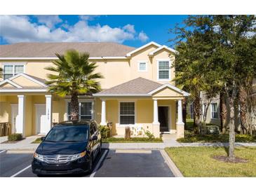 Charming two-story yellow townhome featuring a well-maintained front lawn and covered front porch at 17419 Placidity Ave, Clermont, FL 34714