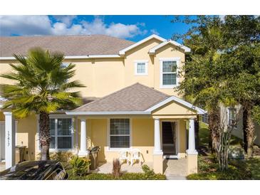 Inviting two-story townhome features a charming covered entryway, two chairs, and lush tropical landscaping at 17419 Placidity Ave, Clermont, FL 34714