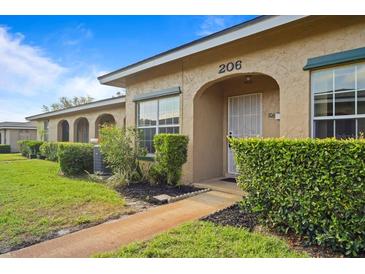Charming tan home exterior with well-maintained landscaping and an inviting arched entryway at 206 Diamond Cv # 106, Casselberry, FL 32707