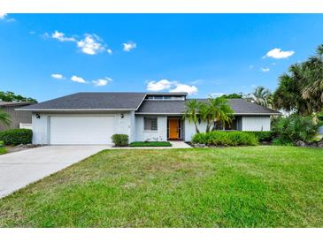 Charming single-story home with a well-manicured lawn and an inviting front entrance with a bright yellow door at 3379 Monika Cir, Orlando, FL 32812
