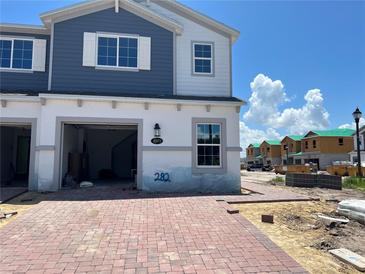 Newly constructed two-story townhome with a brick driveway, an attached garage, and blue and white siding at 4271 Campsite Loop, Orlando, FL 32824