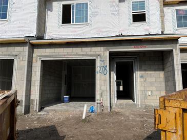 Construction progress showcases an unfinished townhome garage and doorway with block walls and Tyvek weatherproofing at 4287 Campsite Loop, Orlando, FL 32824