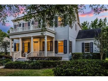 Charming two-story home featuring a welcoming front porch and balcony, complemented by lush landscaping and inviting curb appeal at 1106 Celebration Ave, Celebration, FL 34747