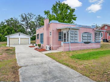 Charming pink home featuring unique architectural details and a detached two-car garage at 16 E Orange Street St, Davenport, FL 33837