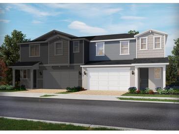 View of two-story townhomes with attached garages, landscaping, and diverse exterior color palettes at 1820 Archer Dr, Minneola, FL 34715