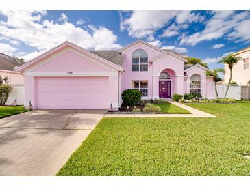 Charming pink two-story home with a well-manicured lawn and a two-car garage at 2712 Rolling Broak Dr, Orlando, FL 32837