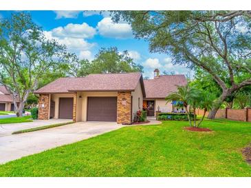 Charming home exterior featuring a well-manicured lawn, mature trees, and a two-car garage at 103 Golf Club Dr, Longwood, FL 32779