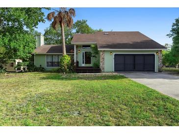 Charming single-story home with a lush green lawn, mature trees, and a two-car garage at 21343 Reindeer Rd, Christmas, FL 32709