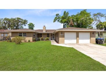 Charming single-story home with a well-maintained lawn and a two-car garage at 2618 Grassmere Ln, Orlando, FL 32808