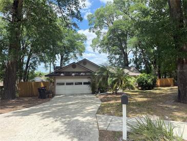 Charming single-story home featuring a two-car garage and a driveway, framed by mature trees and landscaping at 5555 Caurus Ct, Orlando, FL 32808