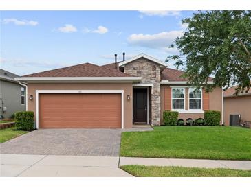 Charming single-story home featuring a stone facade, two-car garage, and well-maintained landscaping at 125 Silver Maple Rd, Groveland, FL 34736