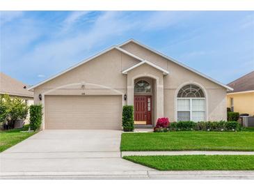 Charming single-story home with a well-manicured lawn, arched windows and a two car garage at 128 Brushcreek Dr, Sanford, FL 32771