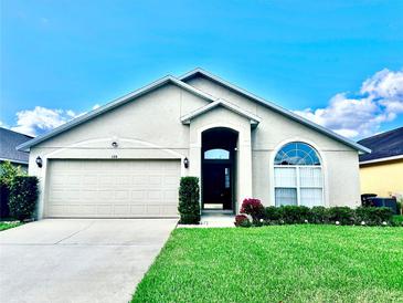 Charming single-story home with an attached two-car garage, arched entry, and manicured landscaping at 128 Brushcreek Dr, Sanford, FL 32771