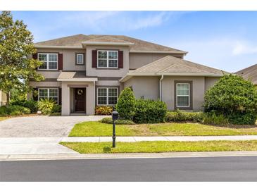 Charming two-story home with a well-manicured lawn, beautiful landscaping, and a paved driveway at 15485 Sandfield Loop, Winter Garden, FL 34787