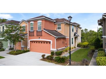 Inviting two-story townhome with a two-car garage and colorful peach and beige exterior at 2112 Rookery Ln, Sanford, FL 32773