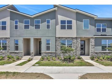 Exterior shot of modern townhouses with stone accents, contemporary design, and manicured landscaping at 2382 Zaballina Pl, Kissimmee, FL 34747