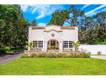 Charming stucco home with terra cotta roof details and a lush, landscaped front yard at 306 Albany Ave, Deland, FL 32724