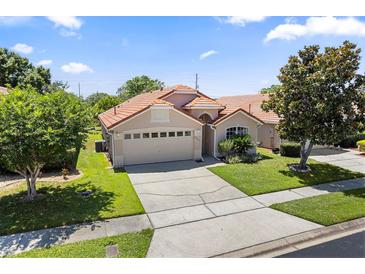 Charming single-story home featuring a two-car garage, beautiful landscaping, and a classic tile roof at 5337 Watervista Dr, Orlando, FL 32821