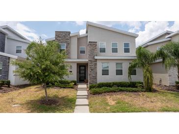Contemporary two-story home featuring a stone facade, well-manicured lawn, and modern architectural details at 780 Drop Shot Dr, Davenport, FL 33896