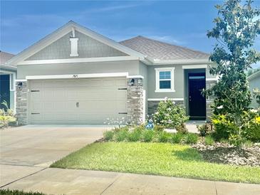 Charming single-Gathering home with a well-maintained lawn, stone accents, and a two-car garage at 7871 Penrose Pl, Wildwood, FL 34785