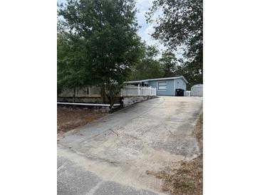 Charming single-story home featuring a long driveway, mature trees, and a well-maintained yard with a picket fence at 1238 Lakecrest Dr, Apopka, FL 32703
