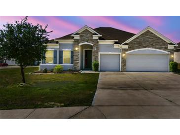 Charming single-story home with a two-car garage, stone accents, and a well-maintained lawn at twilight at 1816 Forest Glen Dr, Fruitland Park, FL 34731