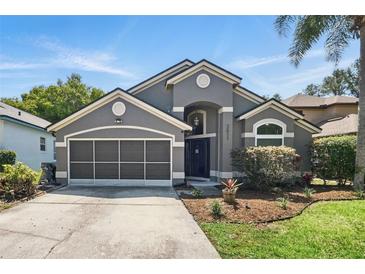 Charming single-story home featuring a gray facade, manicured lawn, and a two-car garage at 2611 Burwood Ave, Orlando, FL 32837