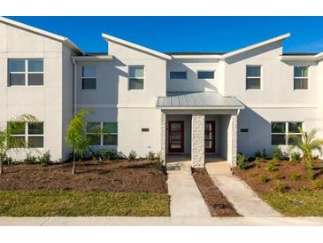 Modern townhome exterior with a clean white facade, symmetrical design, and minimalist landscaping on a sunny day at 3009 Penelope Loop, Kissimmee, FL 34746