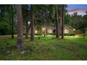Charming brick home surrounded by mature trees and lush landscaping at 324 Old Mill Rd, Enterprise, FL 32725
