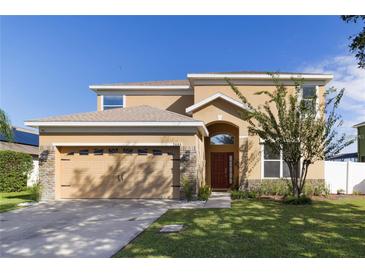 Inviting home with a two-car garage, warm colors, and stone veneer accents at 3680 Ricky Ln, St Cloud, FL 34772